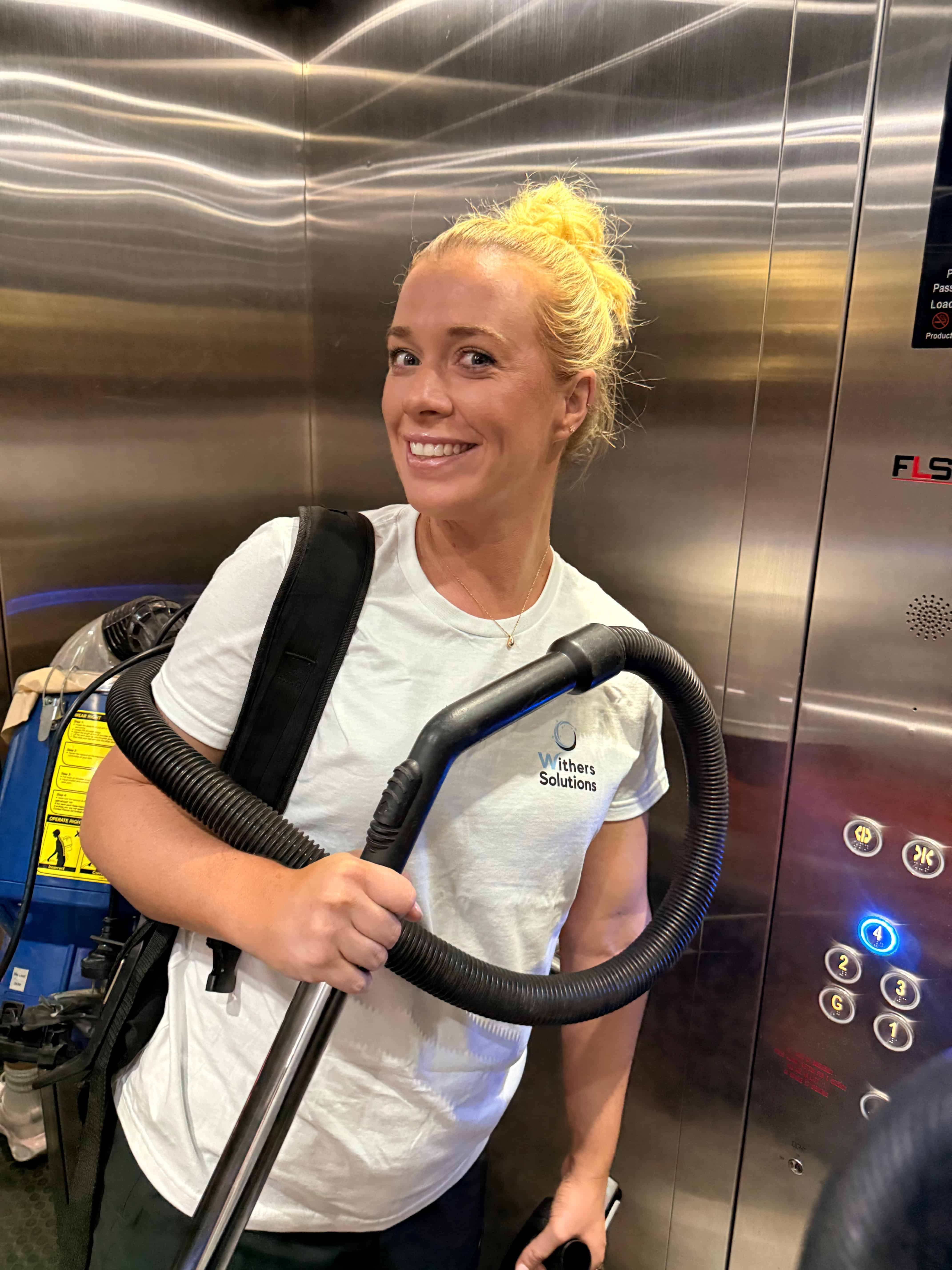 Commercial Cleaning South Yarra 2026 Emma smiling in a lift with the backpack vacuum over her shoulder