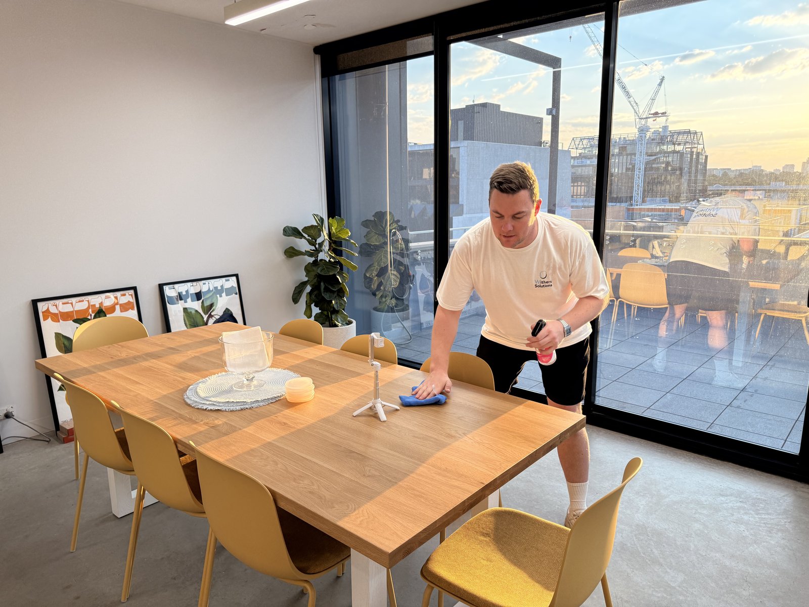 Ryan wiping down a meeting table beside the terrace doors at the Pulp Digital office in Richmond